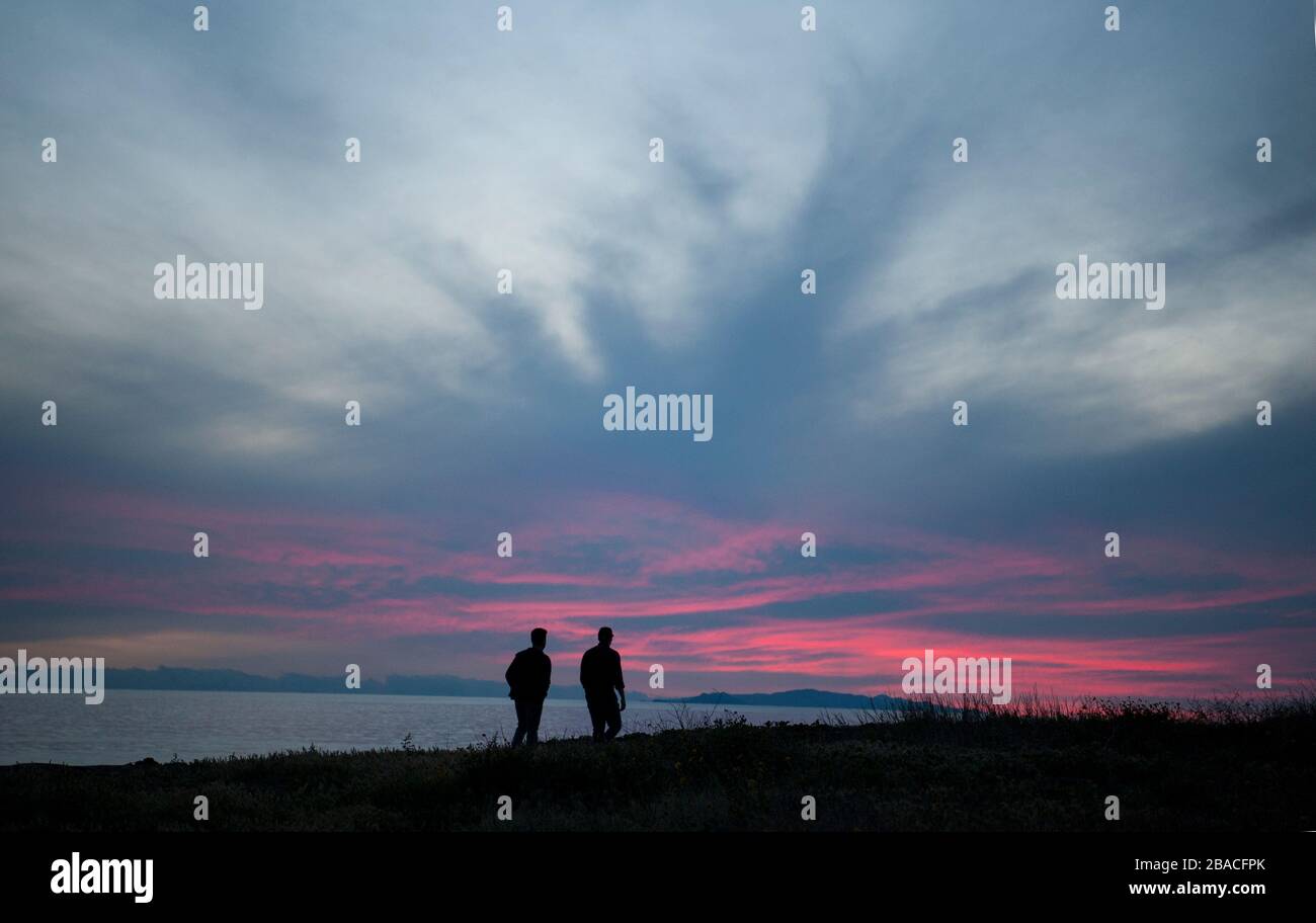 Menschen, die den Sonnenuntergang von Klippen mit Blick auf den Pazifischen Ozean in der Nähe von Malibu, Kalifornien, beobachten. Stockfoto