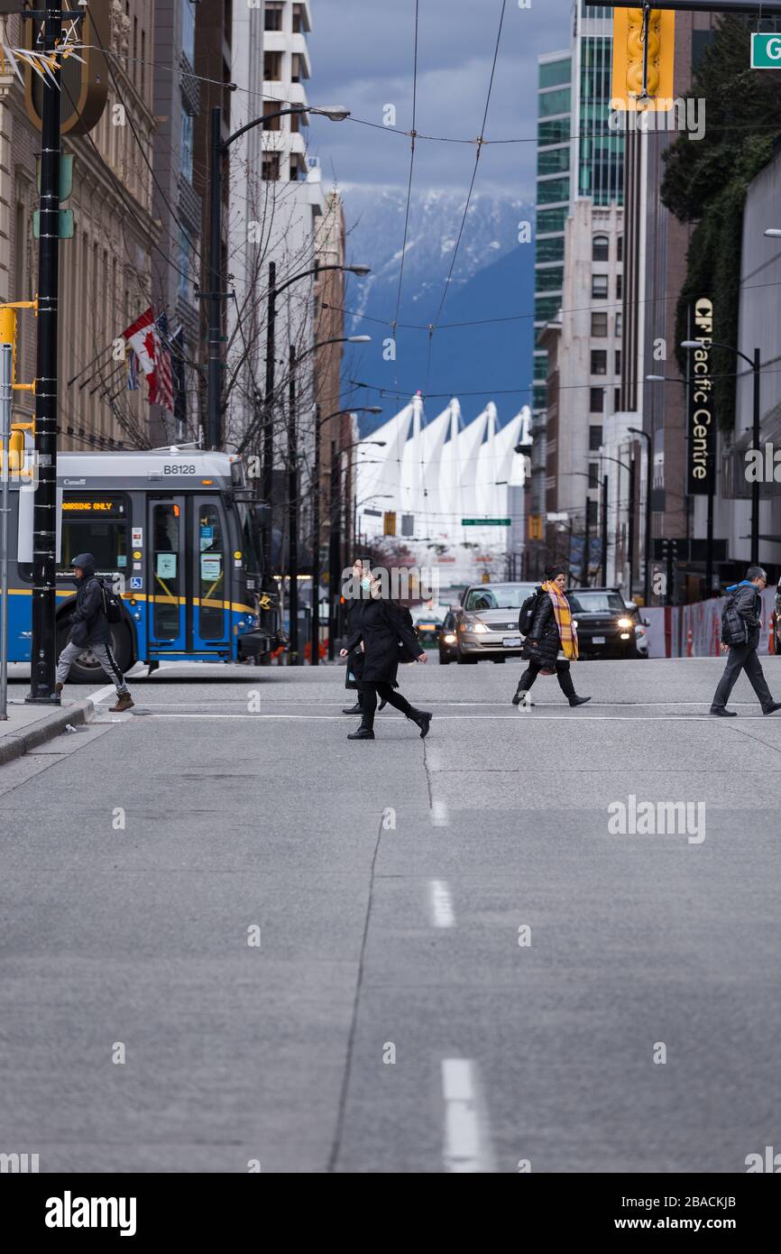 DOWNTOWN VANCOUVER, BC, KANADA - MAR 23, 2020: Fußgänger, die mit medizinischen Gesichtsmasken durch die Innenstadt von Vancouver laufen, um sich vor dem zu schützen Stockfoto