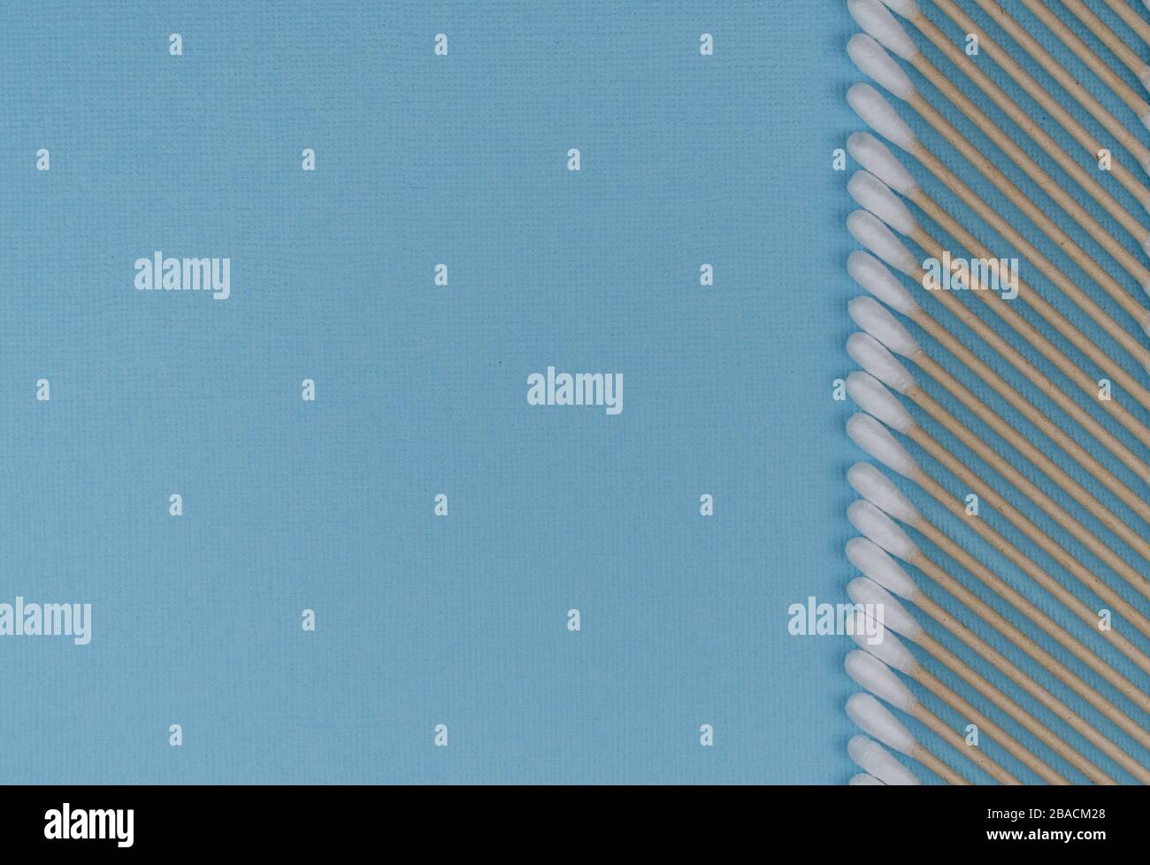 Flache Laienzusammensetzung mit Wattestäbchen auf blauem Grund. Natürliche Baumwollstäbchen aus Baumwolle und Rohrstock. Stockfoto