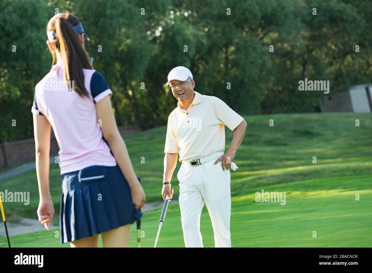 Die jungen Frauen und Senioren spielen Golf Stockfoto