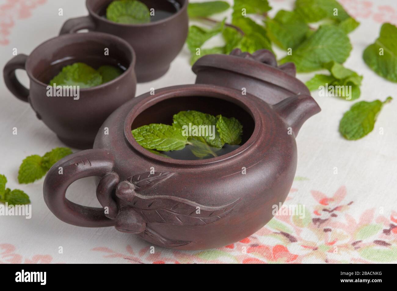 Yixing Tonteapot und zwei Teetassen mit Minzblättern Stockfoto