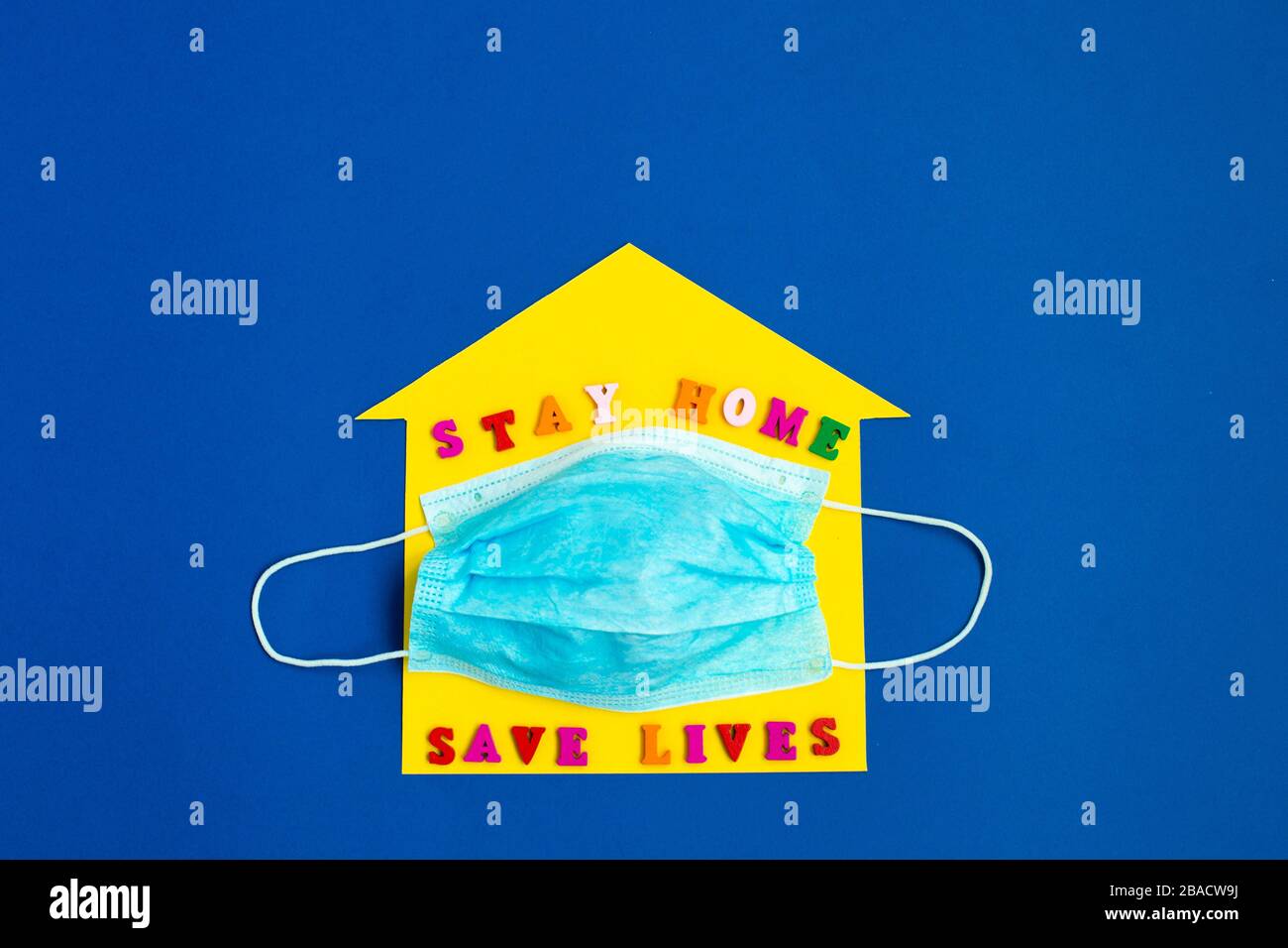 "Stay Home Save Lives"-Ausdruck auf dem gelben Hintergrund und der Einwegmaske. Bleiben Sie sicher, und bleiben Sie zuhause. Retten Sie den Planeten vor dem Corona-Virus. Stockfoto