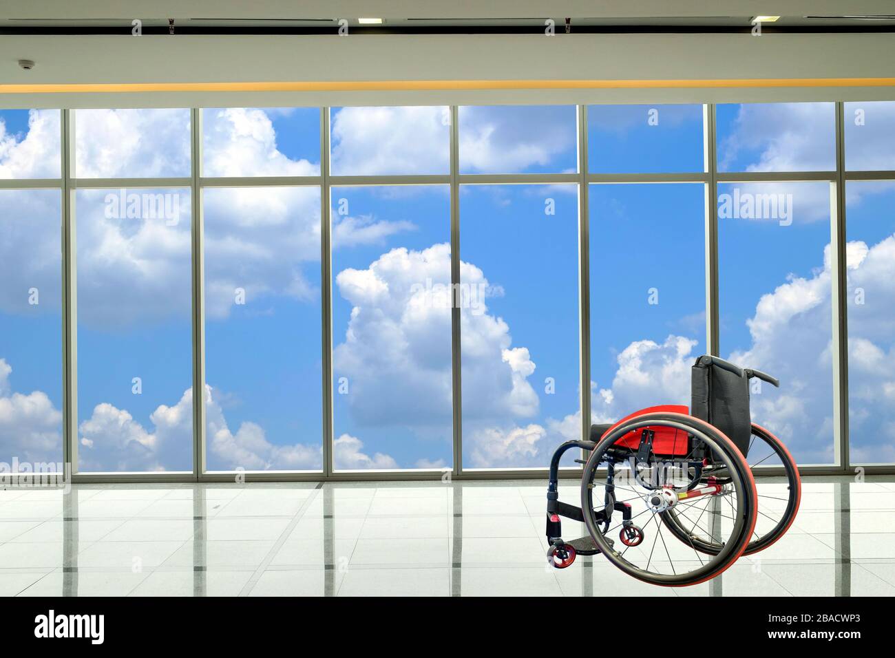 Moderner Rollstuhl, der im leeren Raum mit Wolke- und Himmelshintergrund, Gesundheitskonzept und medizinischem Konzept geparkt ist. Stockfoto