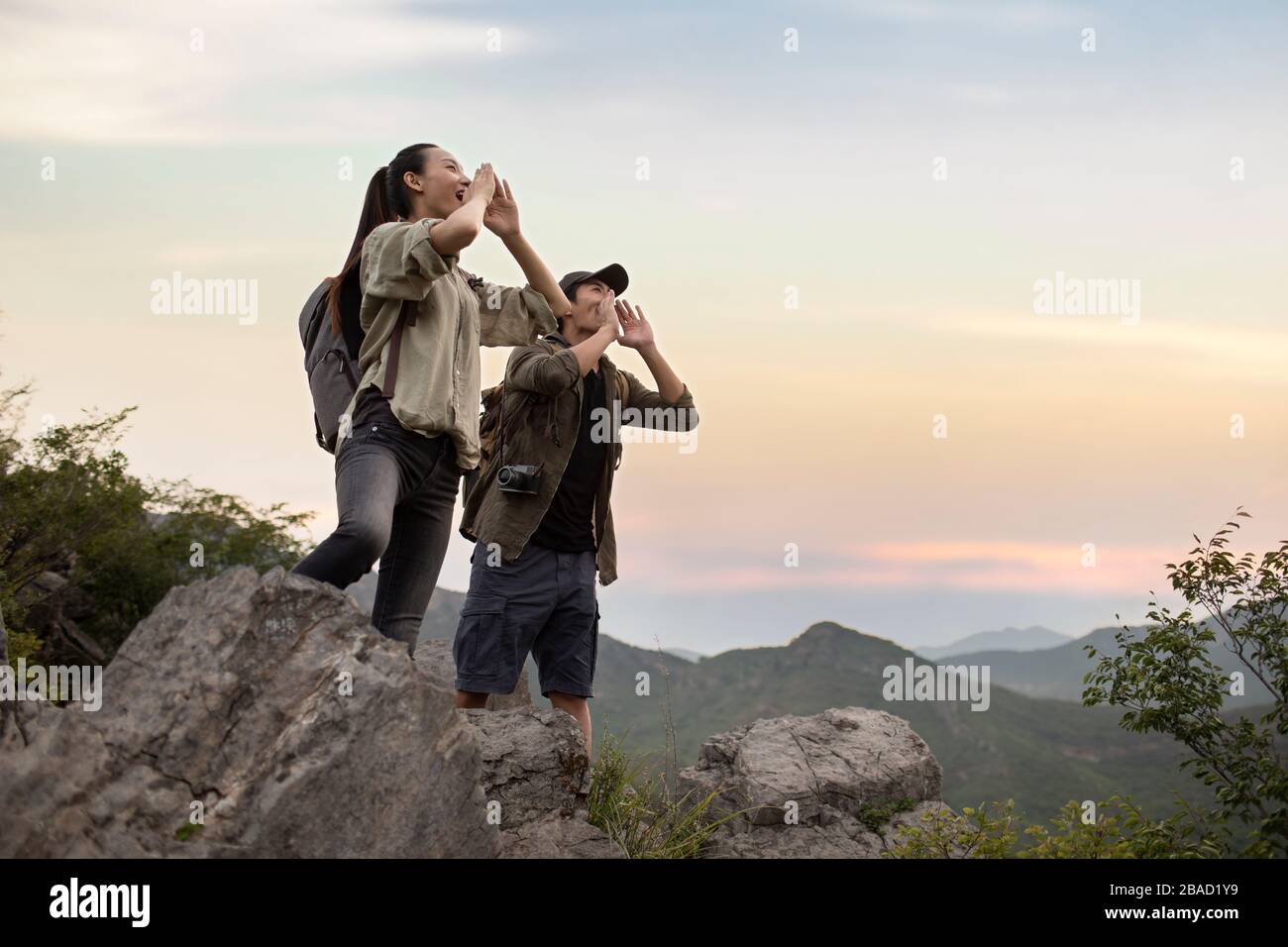 Junges chinesisches Paar, das auf dem Berggipfel schreit Stockfoto