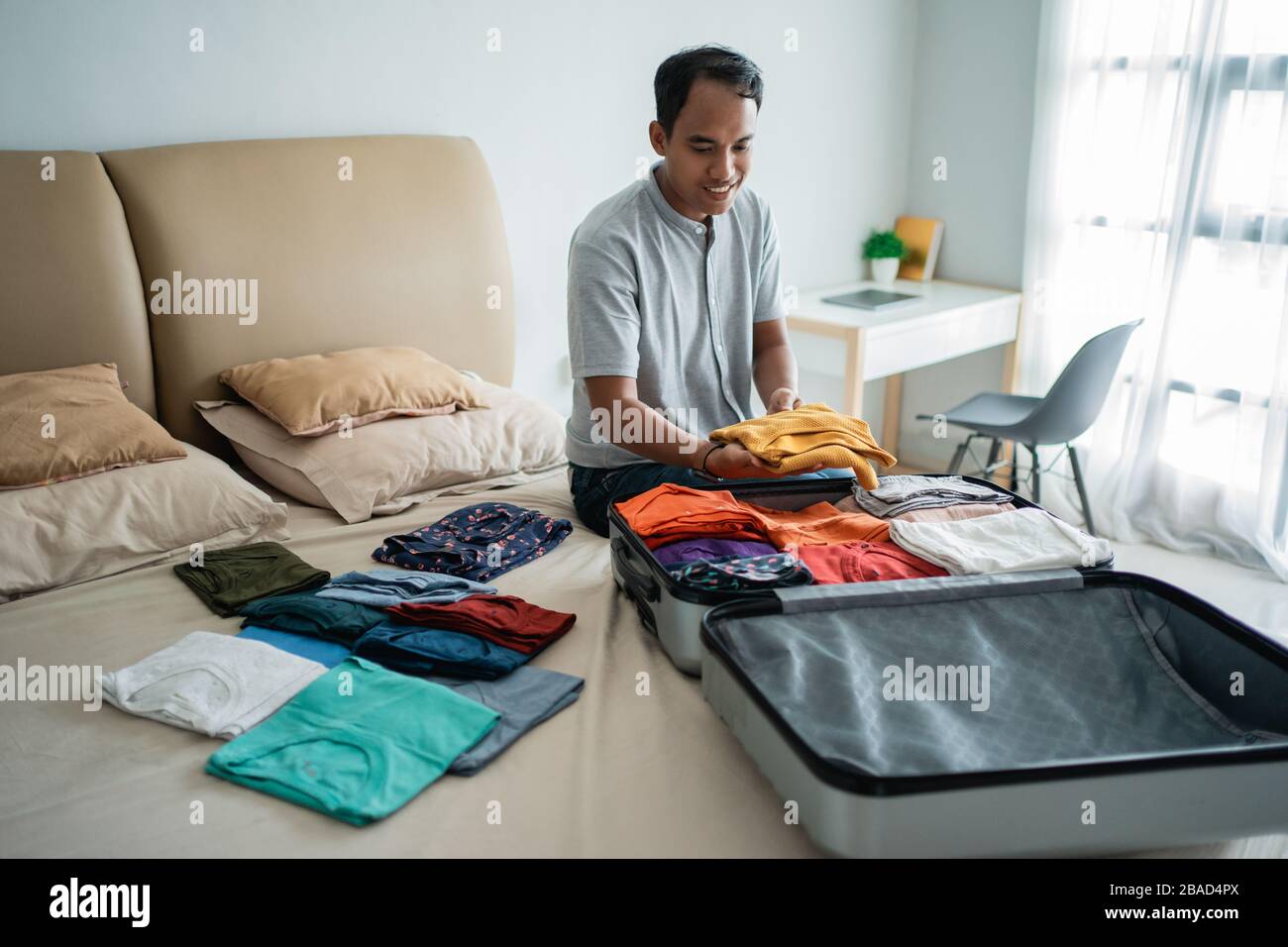 asian man legt seine Kleidung in den Koffer, bevor er in den Urlaub geht Stockfoto