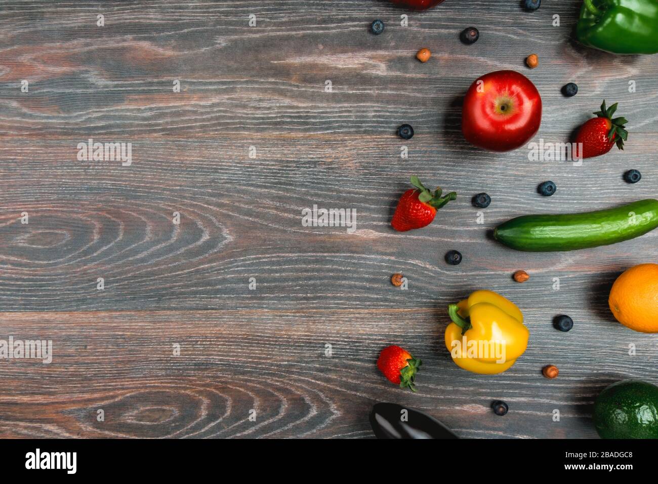 Obst, Gemüse, Nüsse, Beeren liegen auf einem wengenfarbenen Tisch Stockfoto