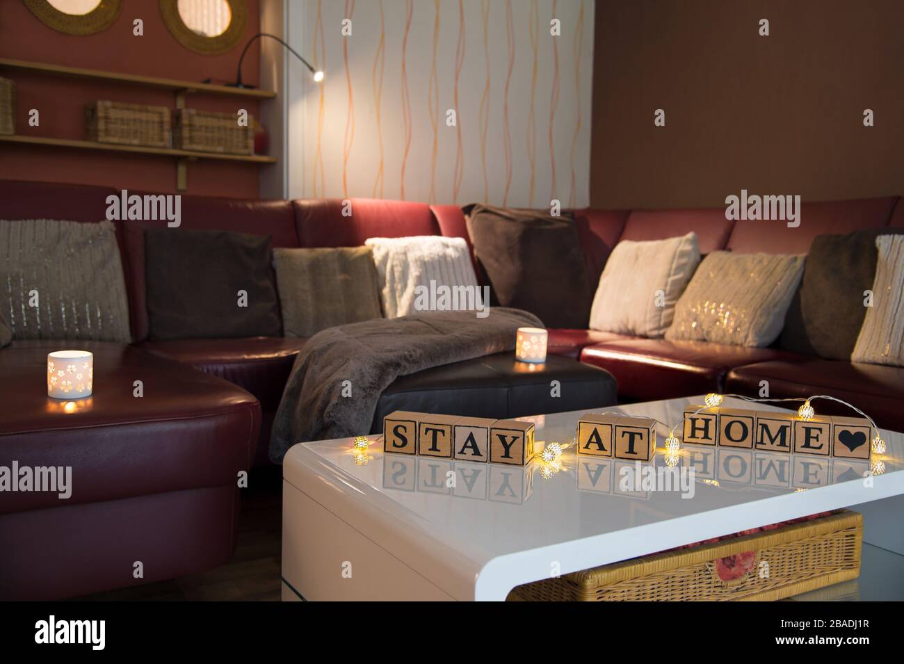 Infektionsrisiko mit Corona-Virus. Modernes Wohnzimmer, Tageslicht. Holzwürfel bilden den englischen Text bleiben zu Hause. Stockfoto