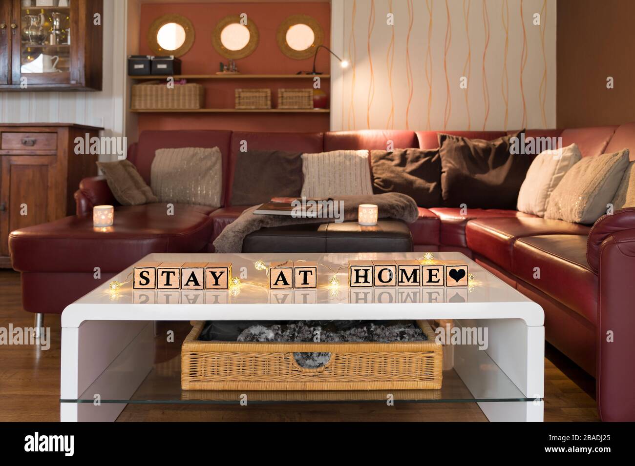 Infektionsrisiko mit Corona-Virus. Modernes Wohnzimmer, Tageslicht. Holzwürfel bilden den englischen Text bleiben zu Hause. Stockfoto