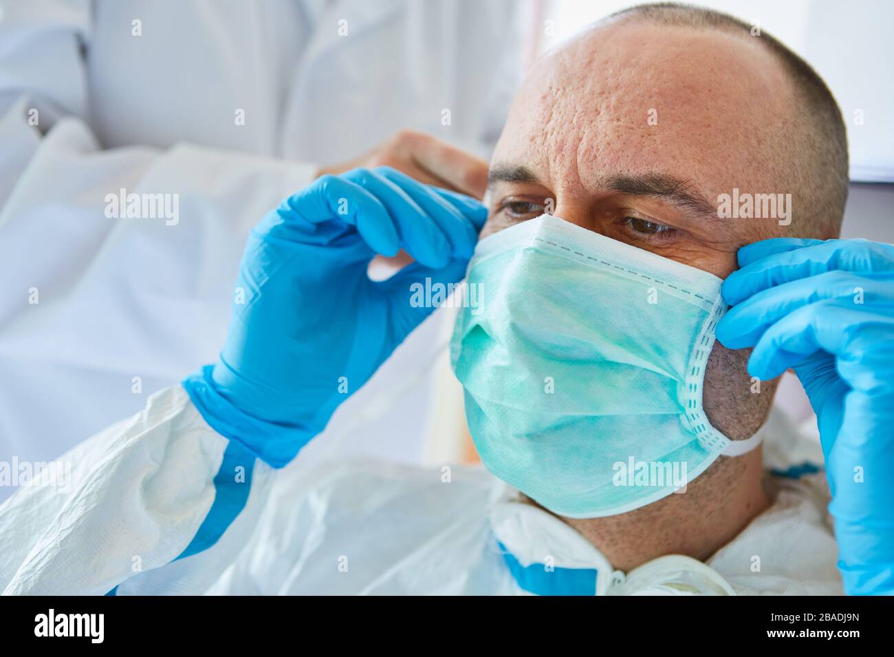 Der Arzt in der Klinik legt während einer Covid-19-Epidemie Schutzkleidung und Gesichtsmaske an Stockfoto