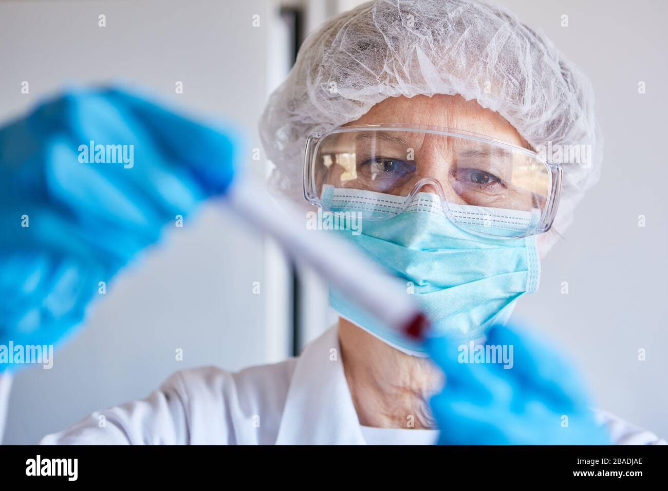 Virologe mit Schutzkleidung und Blutprobe für den Covid-19-Test im Labor Stockfoto