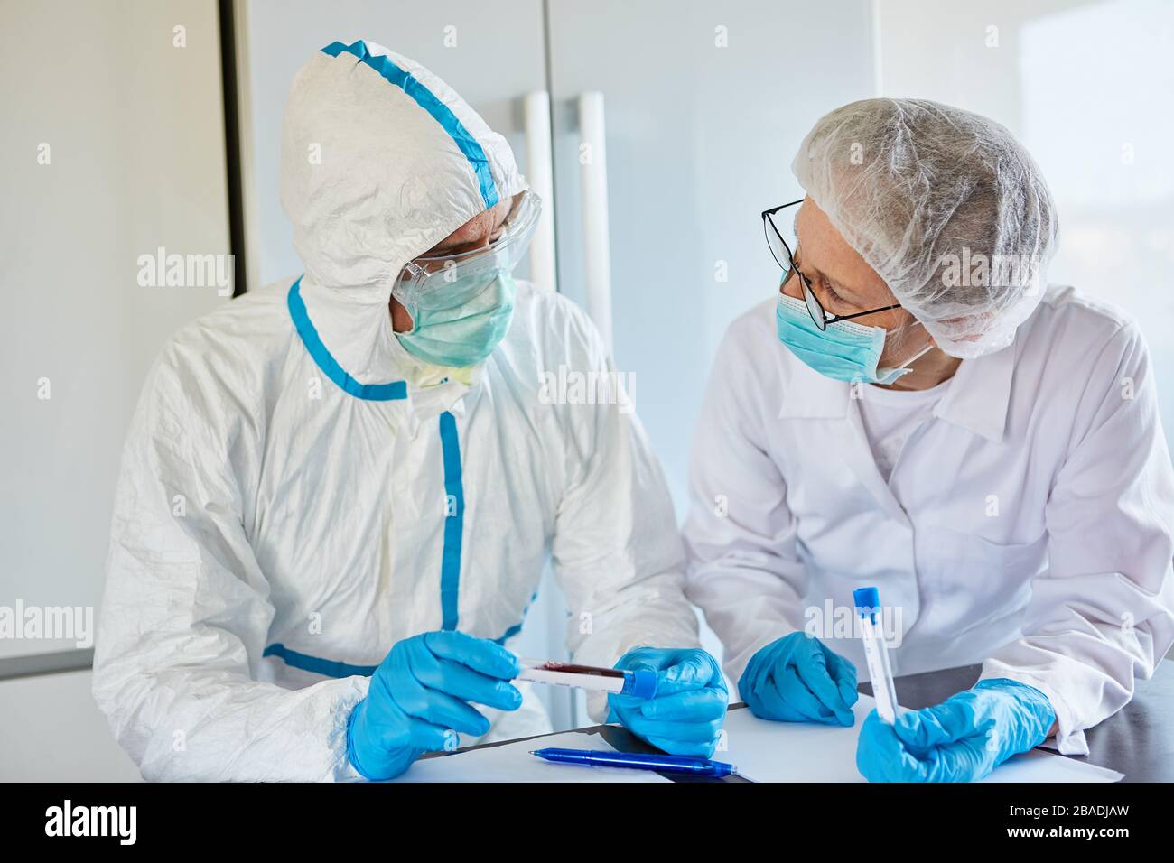 Medizinische Fachkräfte mit Schutzkleidung und Covid-19-Test und Speichelprobe in der Klinik während der Coronavirus-Epidemie Stockfoto
