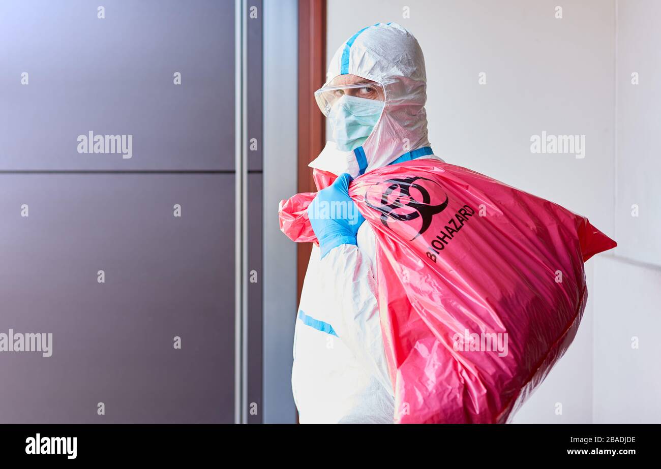 Sauberer bei der Entsorgung infektiöser Abfälle im Krankenhaus mit Schutzkleidung während der Covid-19-Epidemie Stockfoto