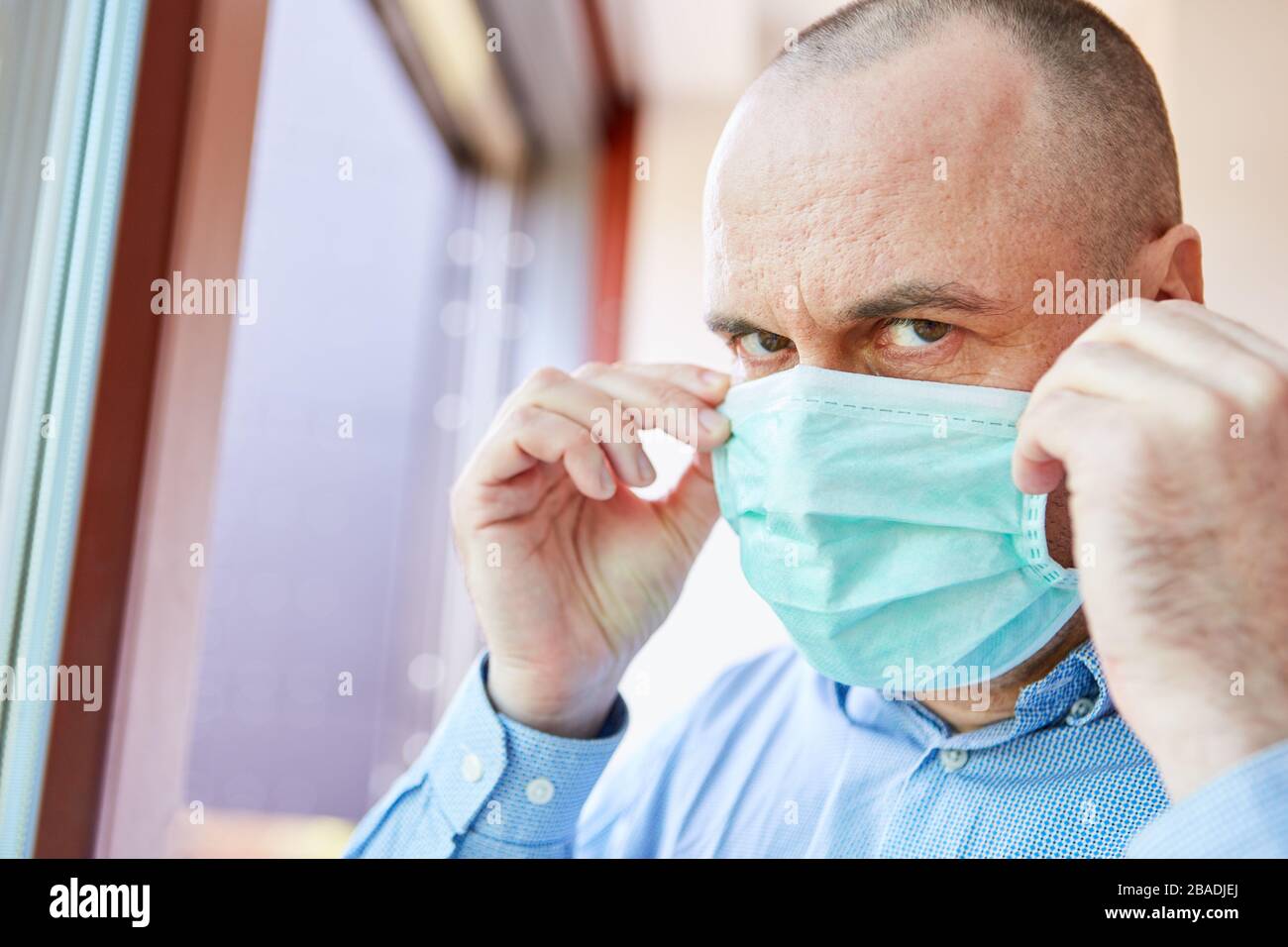 Mann als Covid-19-Patient mit Gesichtsmaske in Quarantäne zu Hause während der Coronavirus-Epidemie Stockfoto