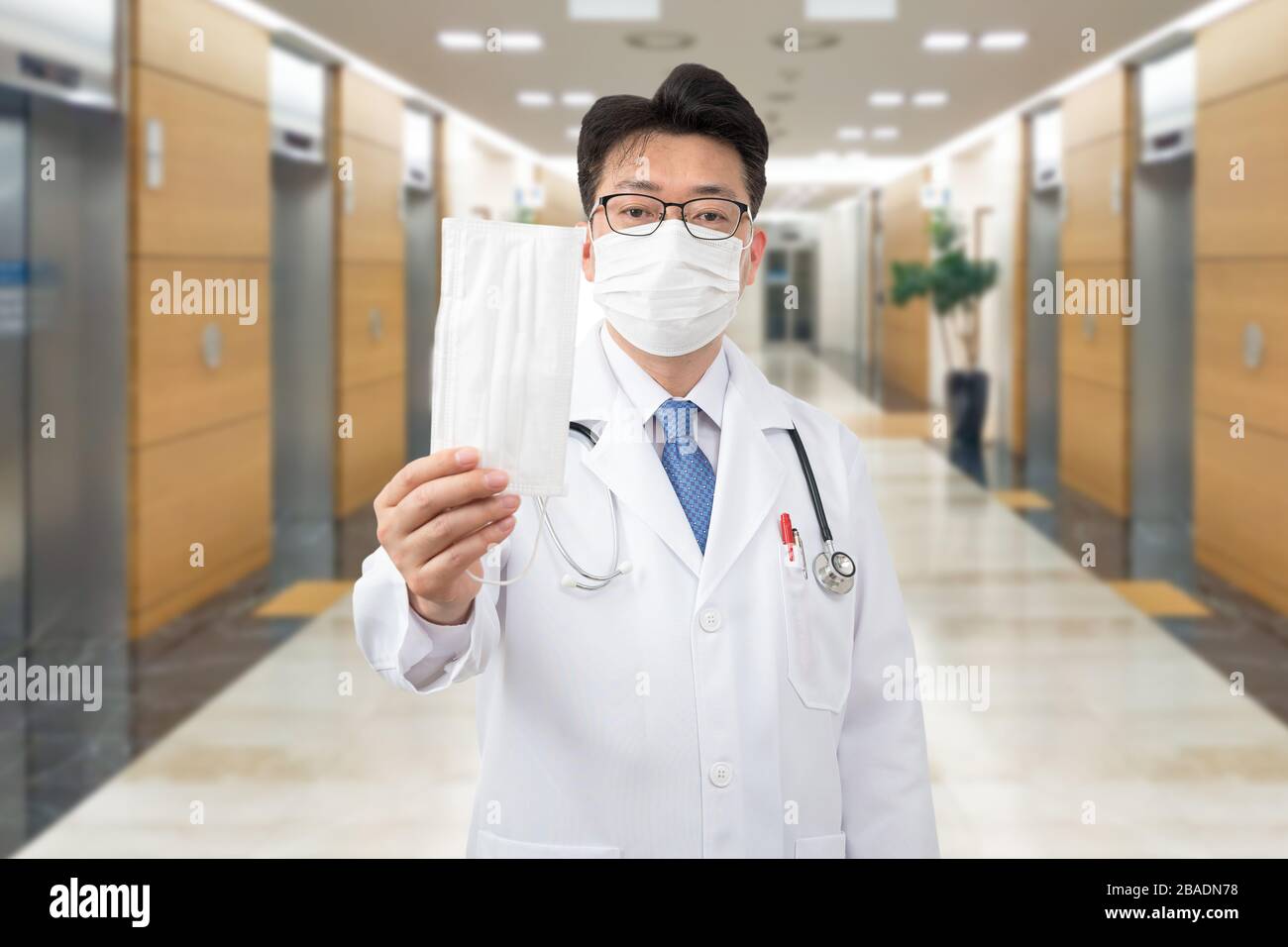 Asiatischer Mittelalter-Arzt, der die Einwegmaske in der Hand hält. Stockfoto