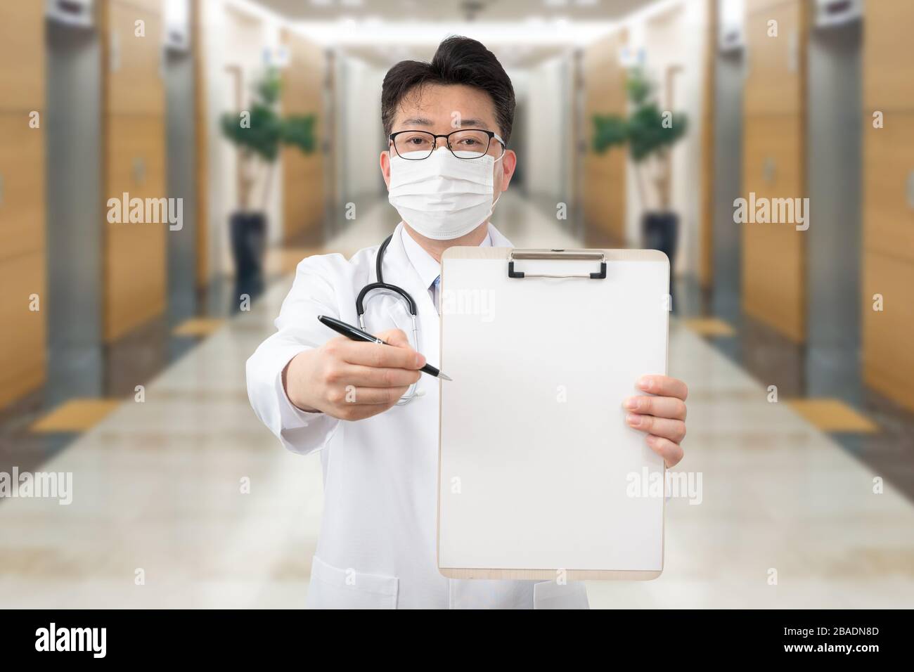 Asiatischer Mittelalter-Arzt mit einer Zwischenablage im Krankenhaus. Stockfoto