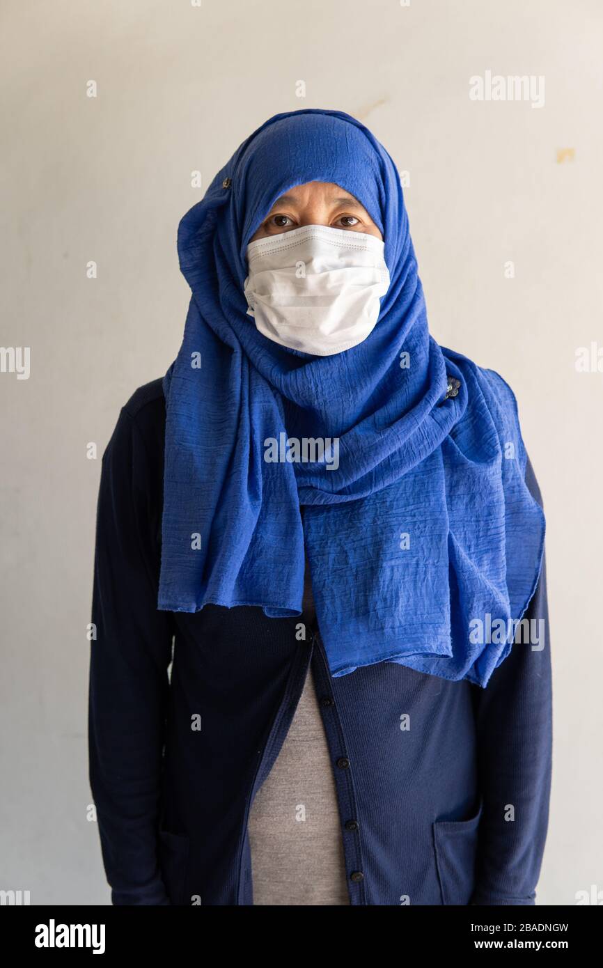 Asian Woman in der medizinischen Maske Coronavirus Pandemie-Krankheit isolieren Hintergrund. COVID-19-Virus von malaysischer Epidemie bis hin zu globaler, indonesischer Konce Stockfoto