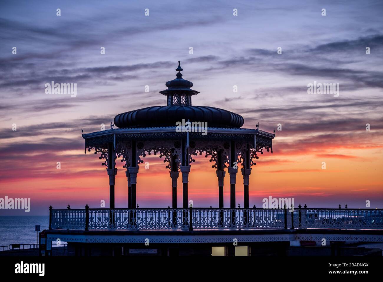 Brighton, Großbritannien, 26. März 2020, die Sonne untergeht heute Abend hinter dem Bandstand an der Küste von Hove, während sich das Land gegen das Coronavirus isoliert. Stockfoto