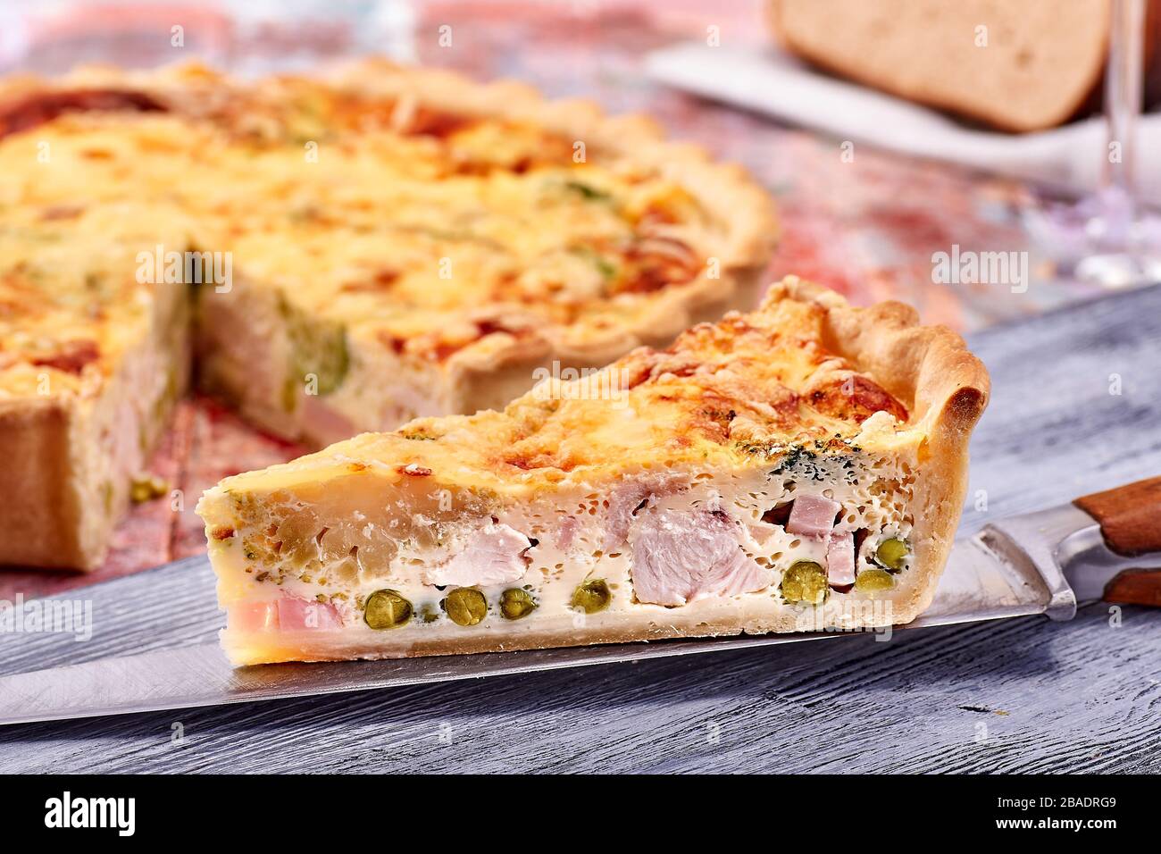 Quiche mit Schinkengemüse auf farbenfrohem Holzhintergrund Stockfoto