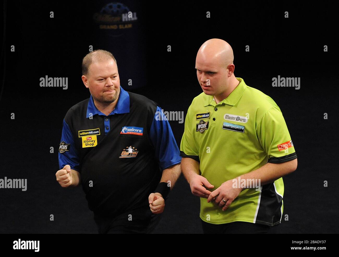 Raymond van Barneveld feiert das gewinnen eines Beins während des Finales, als Michael van Gerwen niedergeschlagen steht Stockfoto