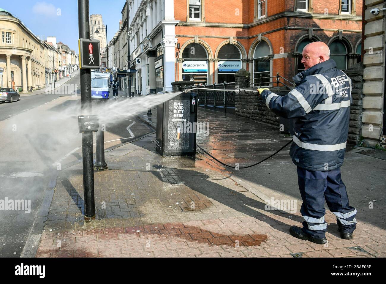 Arbeiter des Bristol City Centre Business Improvement District (BID) reinigen die öffentlichen Bereiche mit hohem Kontakt rund um Park Street und College Green, Bristol mit heißem Wasser mit Desinfektionsmittel und einem Hochdruckschlauch, da Großbritannien weiterhin in Sperrungen ist, um die Ausbreitung des Coronavirus einzudämmen. Die Reinigungsopertaion konzentriert sich auf Oberflächen, die einen hohen Kontakt mit der Öffentlichkeit haben. Stockfoto