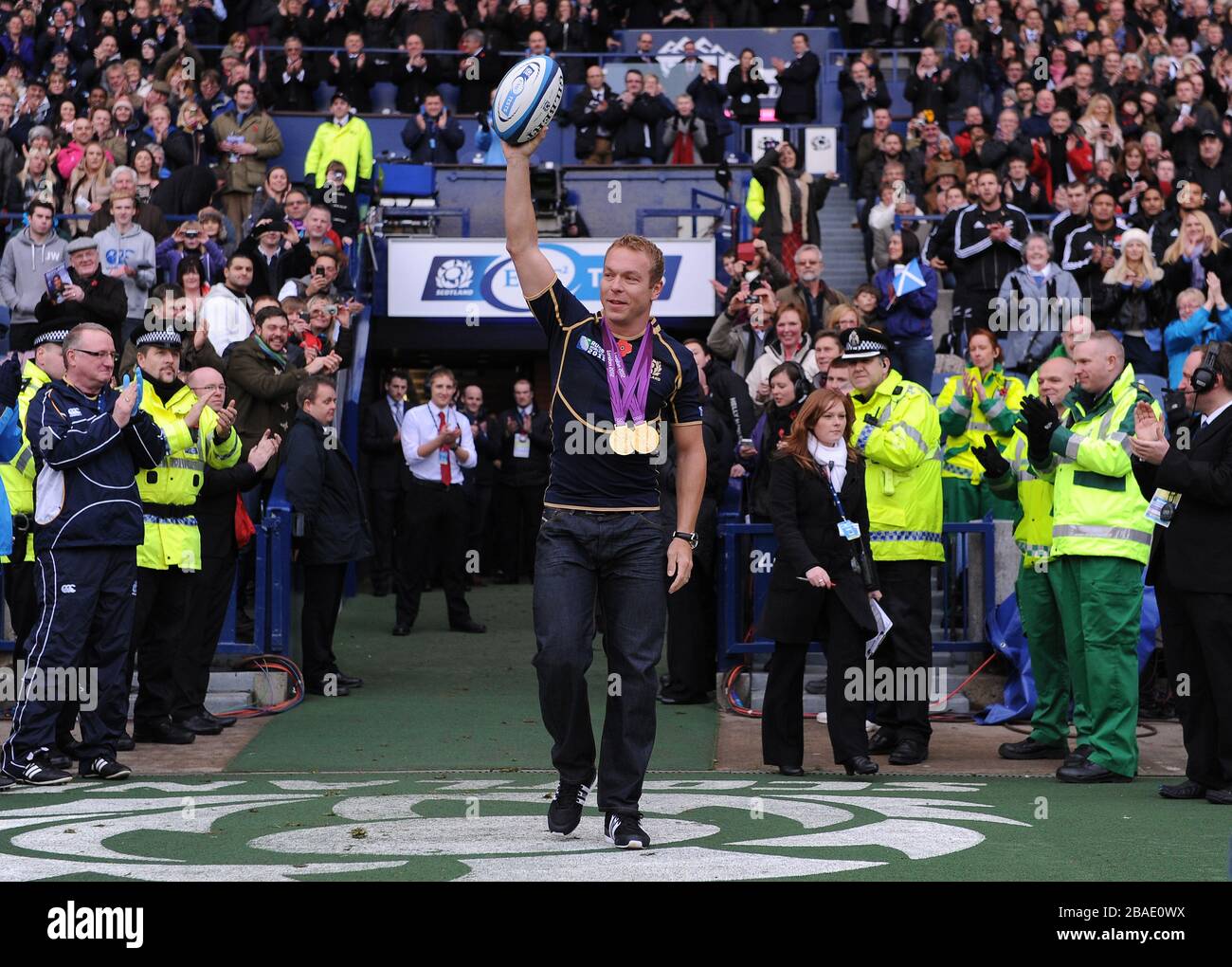 Großbritanniens Olympia-Goldmedaillengewinner Sir Chris Hoy trägt den Spielball auf das Spielfeld Stockfoto