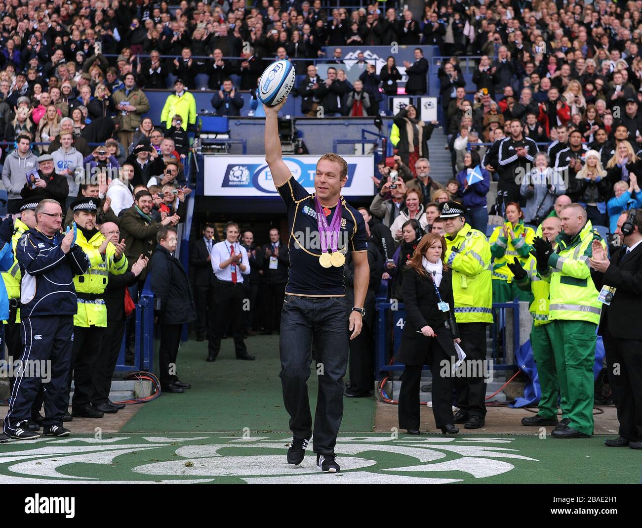 Großbritanniens Olympia-Goldmedaillengewinner Sir Chris Hoy trägt den Spielball auf das Spielfeld Stockfoto