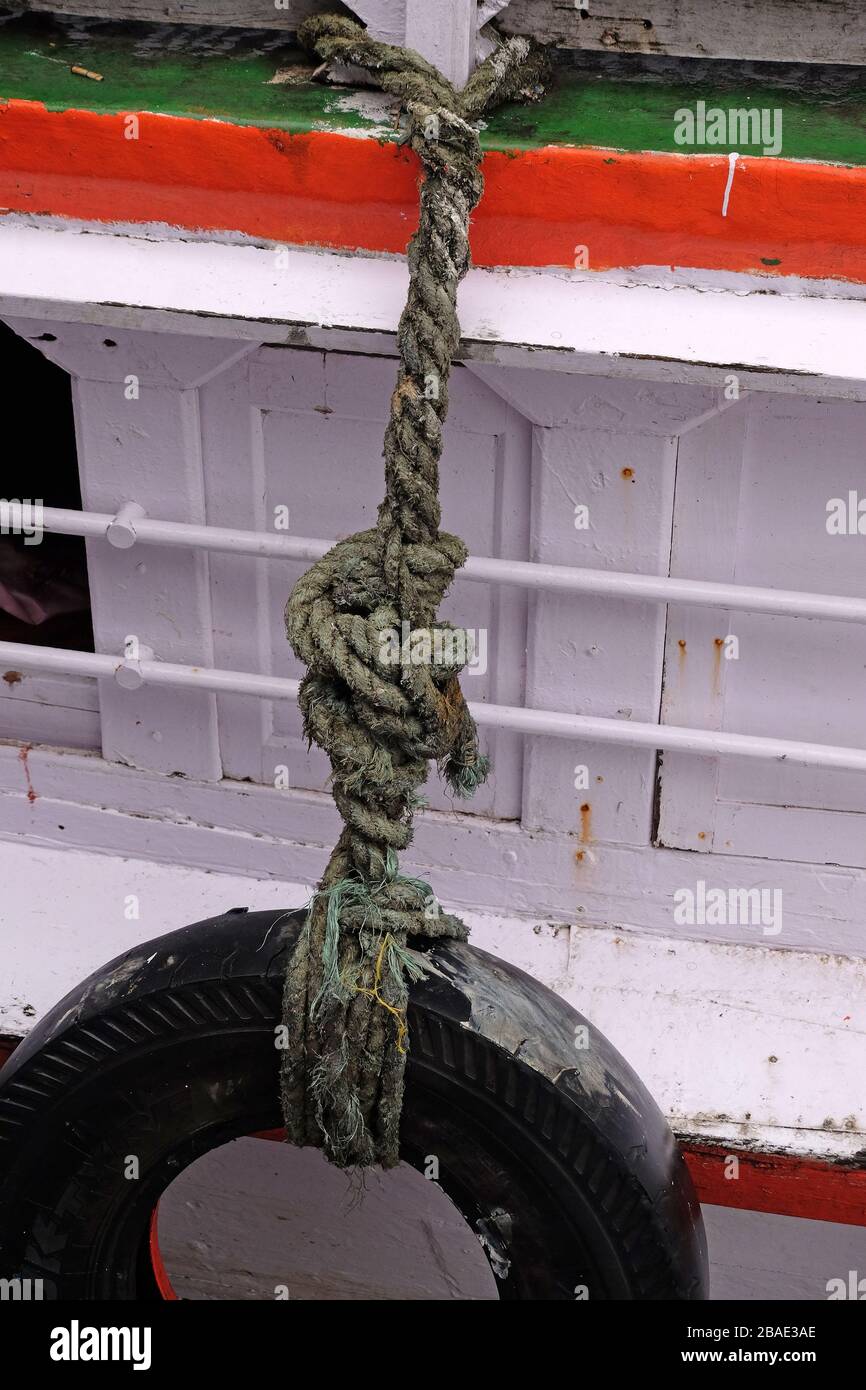 Alte gebrauchte Reifen mit Seil an der Seite des Bootes für den Kotflügel Stockfoto