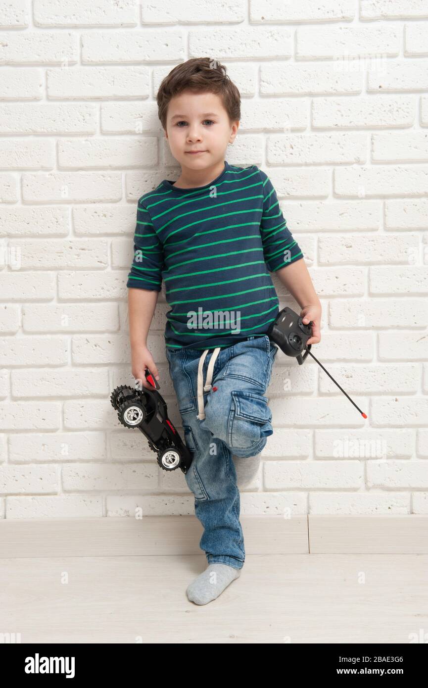 Junge mit Spielzeugauto gegen eine Ziegelwand Stockfoto