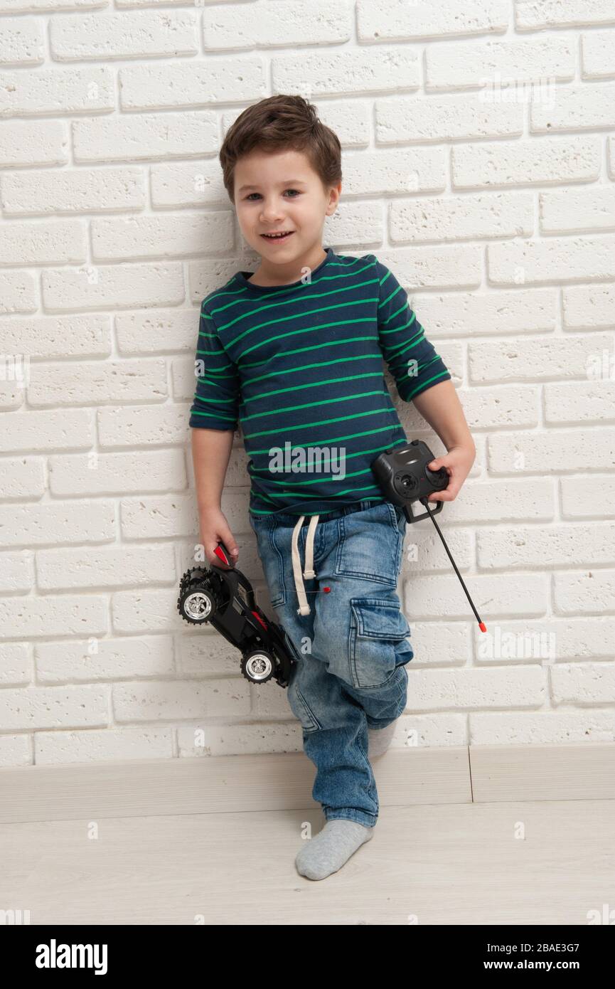 Junge mit Spielzeugauto gegen eine Ziegelwand Stockfoto