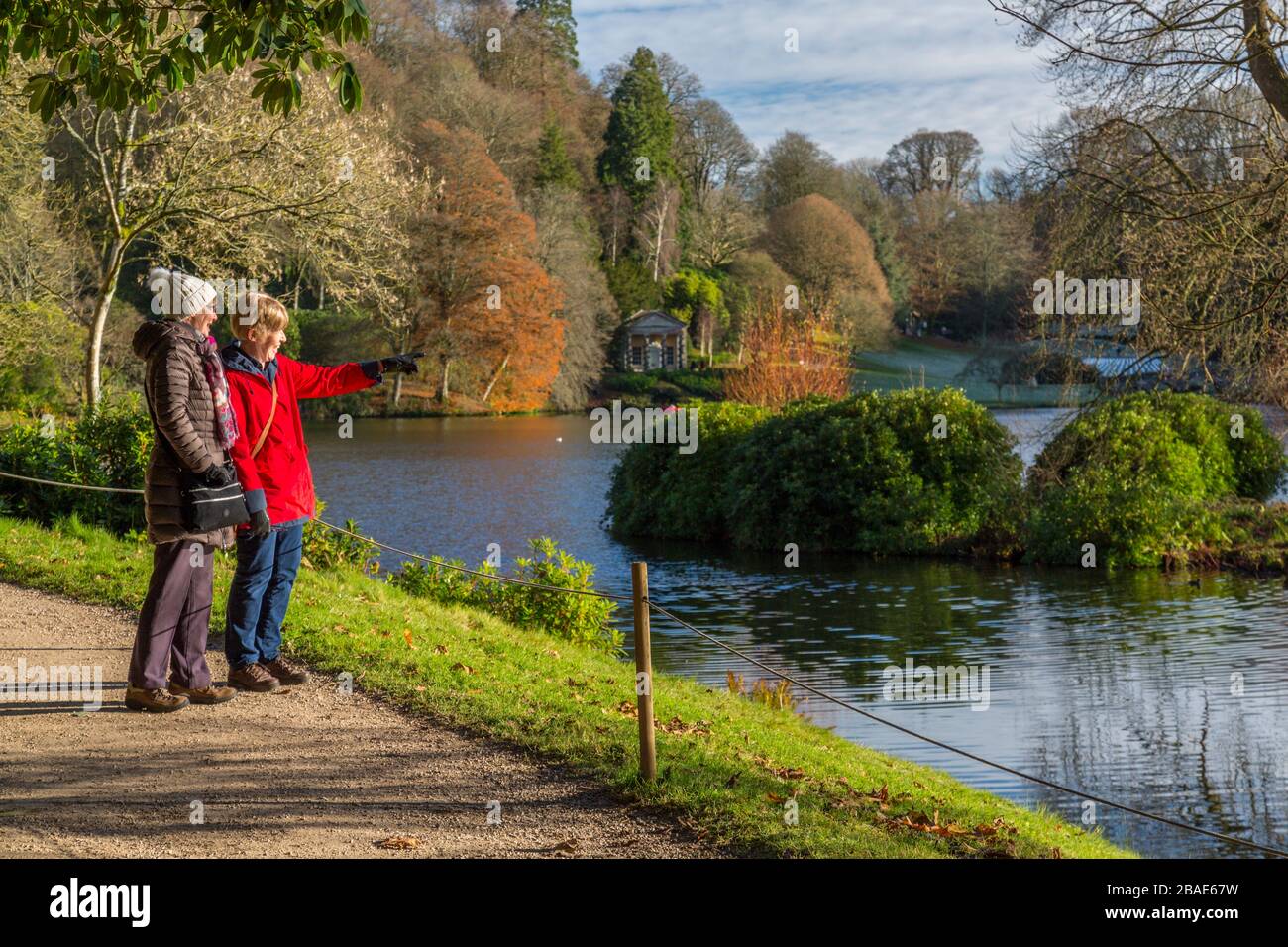 Besucher sehen etwas Interessantes über den See in Stourhead Gardens, Wiltshire, England, Großbritannien Stockfoto