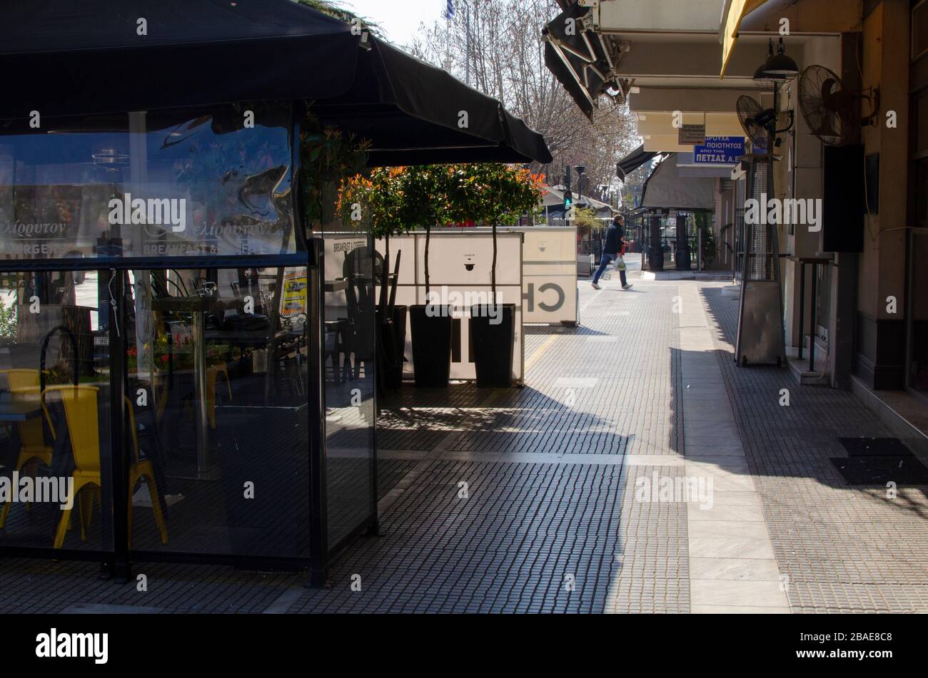 ALEXANDROUPOLI, GRIECHENLAND - 21. März 2020 - EIN Mann spaziert an einem der vielen verschlossenen Cafés im Stadtzentrum von Alexandroupoli, Griechenland vorbei. Die meisten Geschäfte, Cafés, Bars Stockfoto