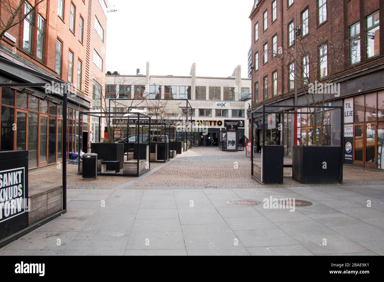 Aarhus, Dänemark - 24. märz 2020: St. Knots Torv in Aarhus, mit Geschäften und Kino im Hintergrund, einem Obdachlosen links liegend und schlafend Stockfoto