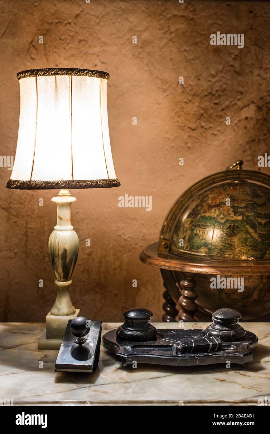 Stll Leben des Marmortischs aus dem 19. Jahrhundert mit Lampe, Globus und antiquem Papiergewicht aus schwarzem Marmor. Stockfoto