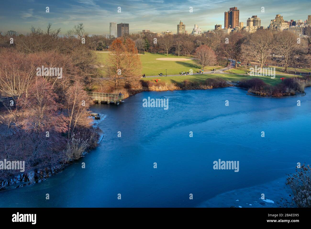 Central Park im NYC Tageslicht Blick im Winter Weitwinkel mit gefrorenem See, Menschen zu Fuß, Skylines und Wolken im Himmel im Hintergrund Stockfoto