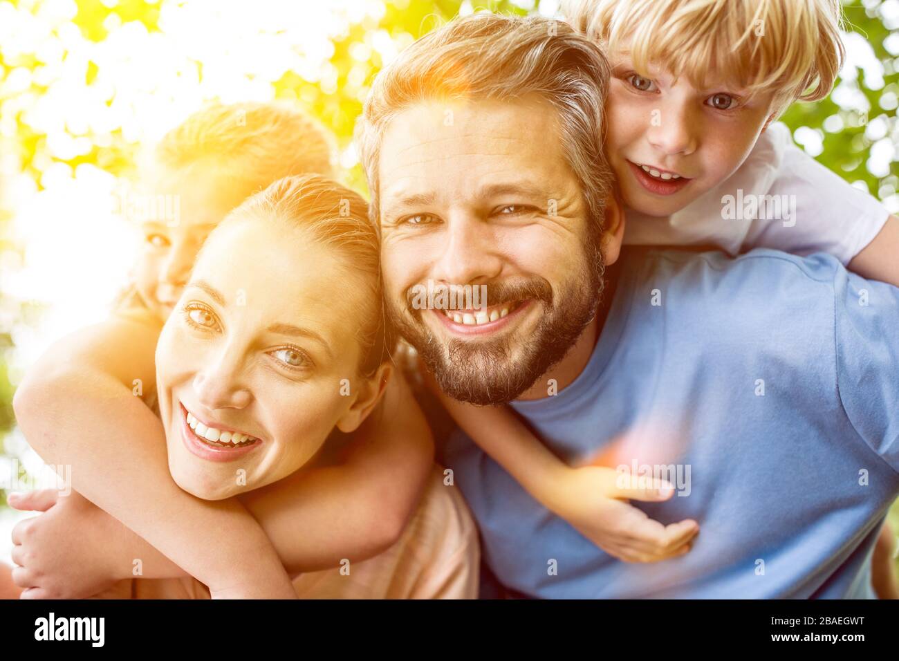Zwei glückliche Kinder werden im Garten von ihren Eltern in den Huckepack gestellt Stockfoto