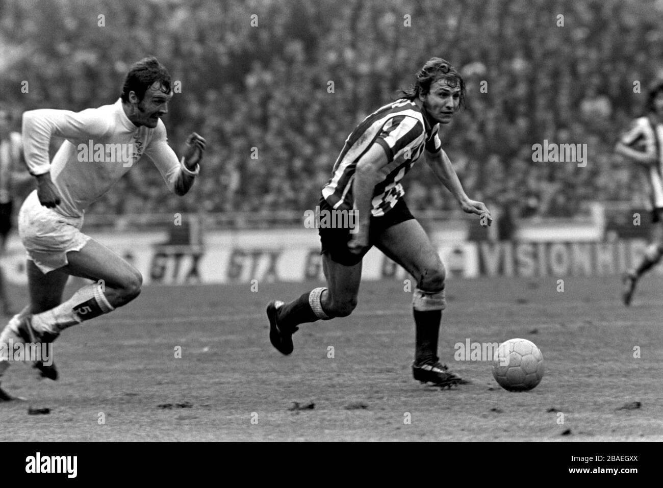 Dennis Tueart of Sunderland (l) kommt von Leeds United Paul Madeley (r) weg Stockfoto