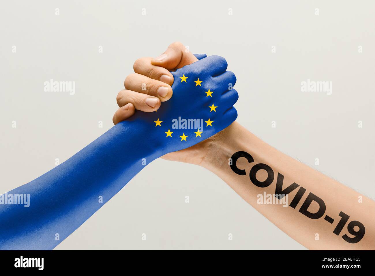 Menschliche Hände, die in der Flagge der Europäischen Union und des Coronavirus eingefärbt sind - Begriff der Virusverbreitung. Das Händeschütteln ist Gefahr, die Art und Weise der weltweiten Epidemie. Bleiben Sie sicher. Prävention, Sicherheit, Pandemiekonzept. Stockfoto