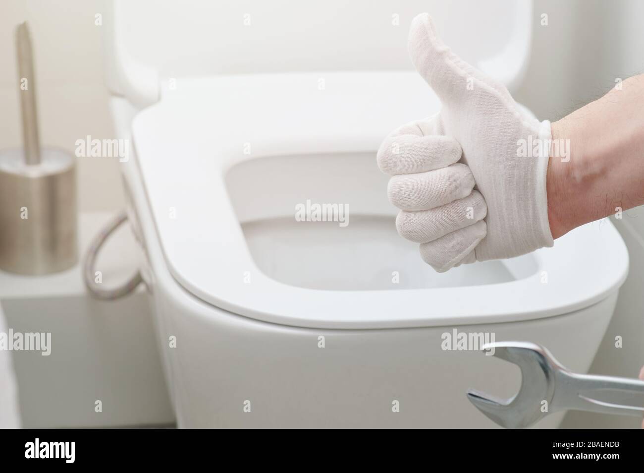 Klempner zeigen Daumen nach oben auf dem hintergrund des toilettensitzes Stockfoto