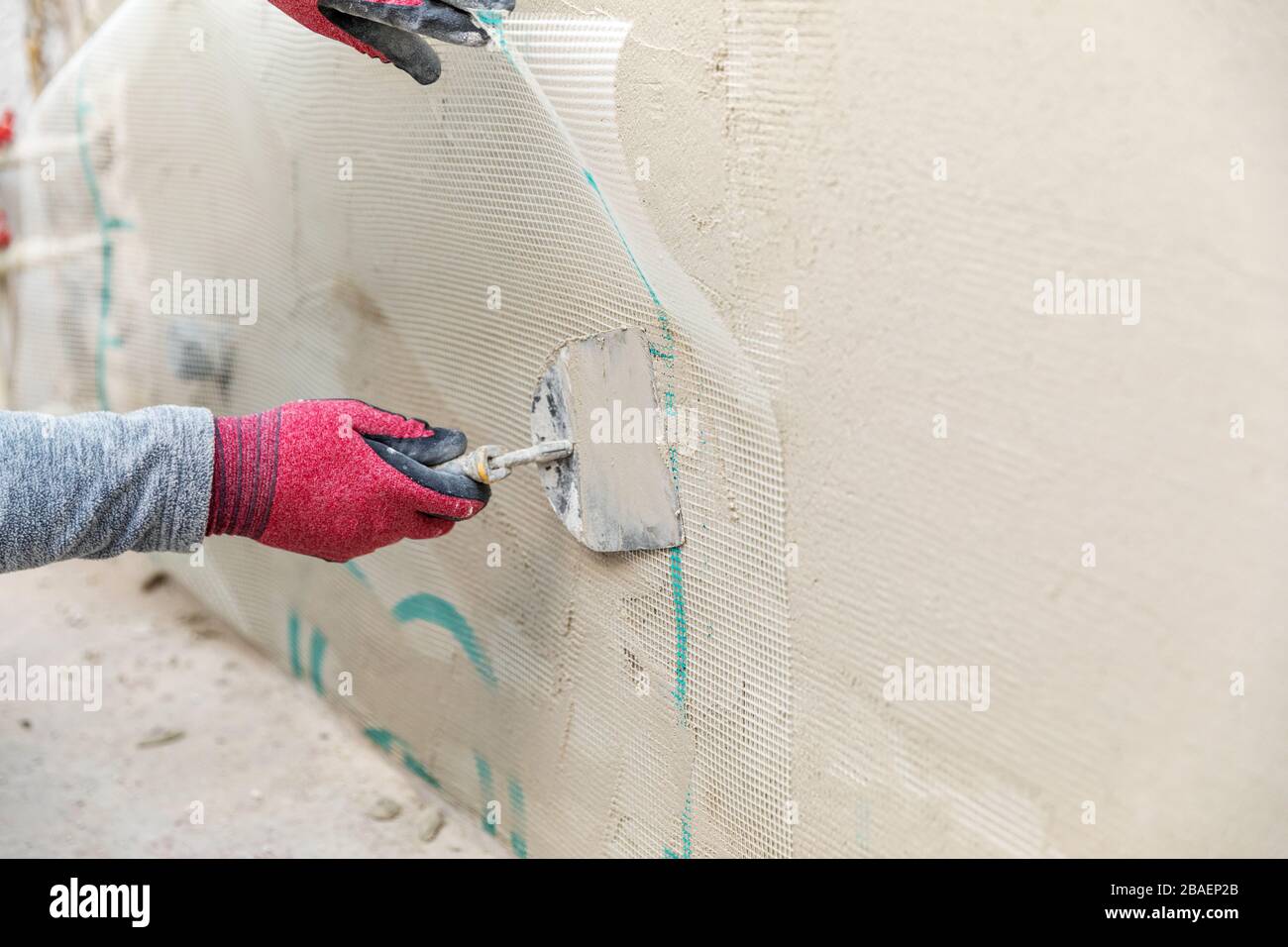 Bauarbeiter installieren Glasfaser-Putzgitter an der Wand Stockfoto