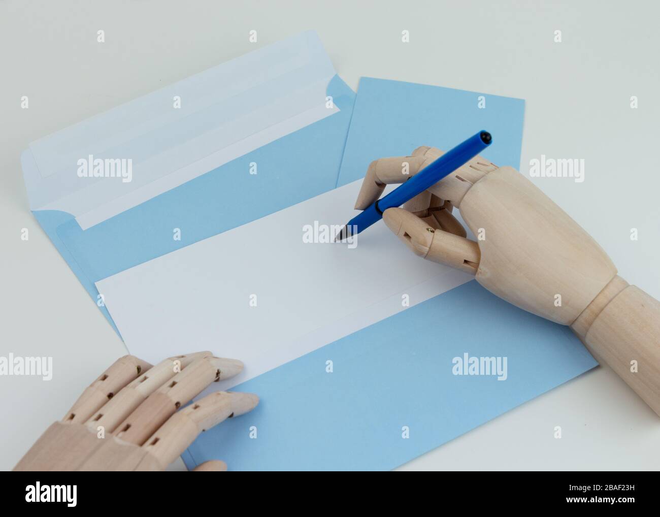 Holzhände halten Stift und Umschlag und leeren Brief. Draufsicht. Stockfoto