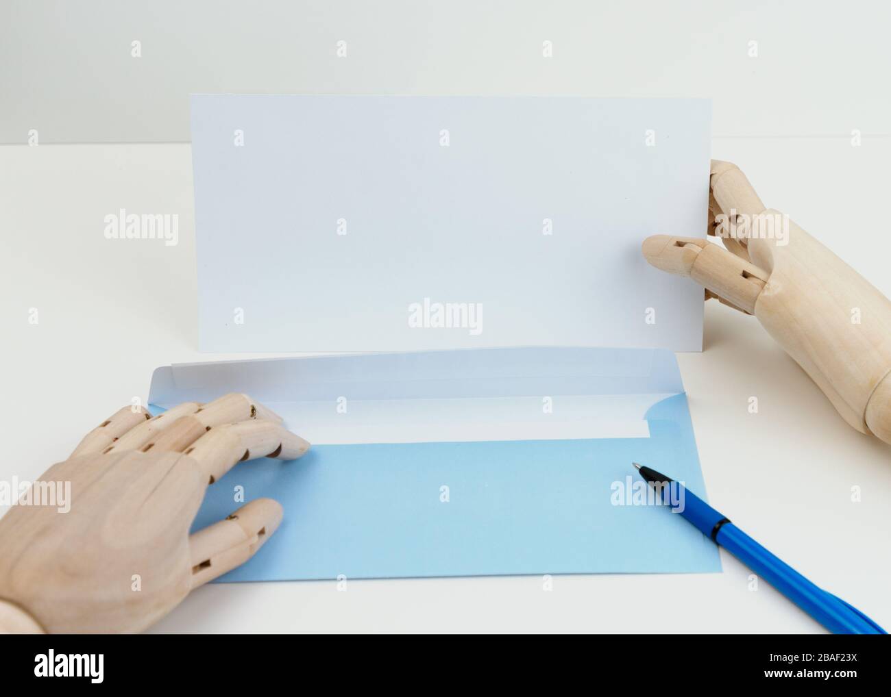 Holzhände halten Stift und Umschlag und leeren Brief. Draufsicht. Stockfoto