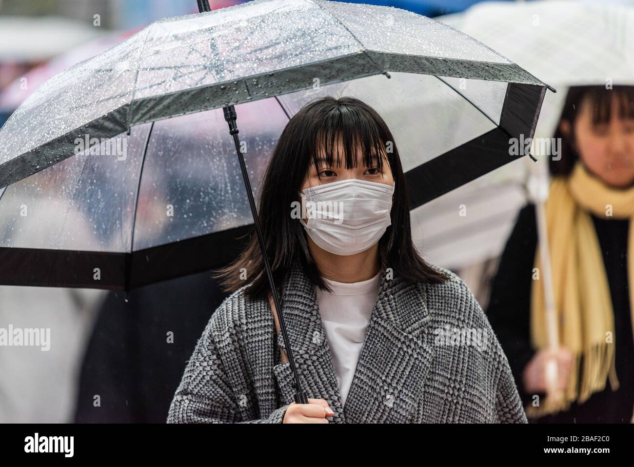 Tokio, Japan - 10. März 2020. Frau, die nach einer globalen Coronavirus-Pandemie an einem regnerischen Tag in Tokio eine Maske trägt. Stockfoto