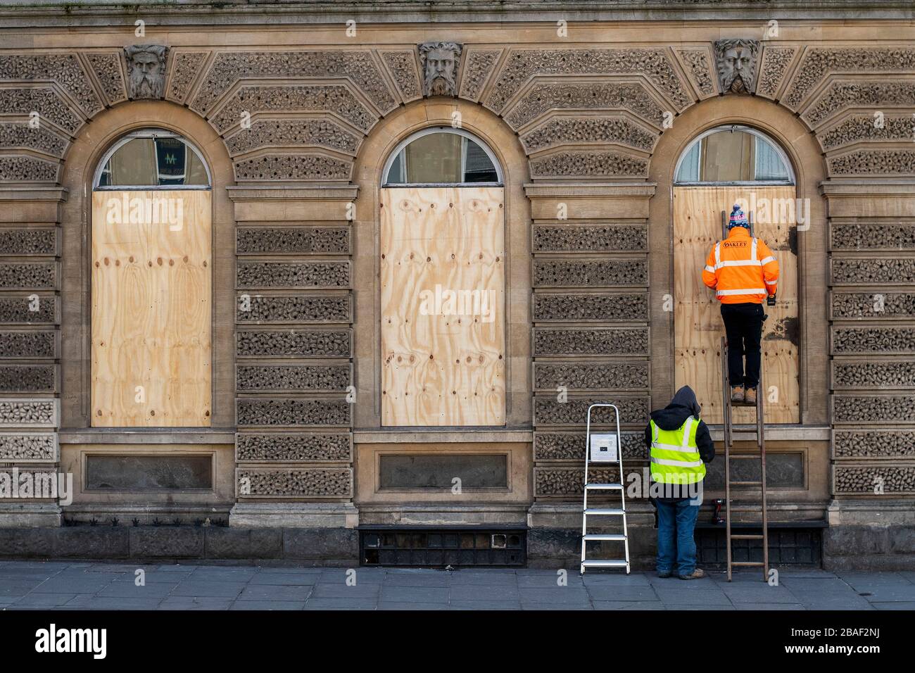 Arbeiter steigen in die Fenster eines Restaurants in Bath, Somerset, nachdem die britische Regierung strikte Einschränkungen angekündigt hatte, um Coronavirus zu versuchen und einzudämmen. Stockfoto