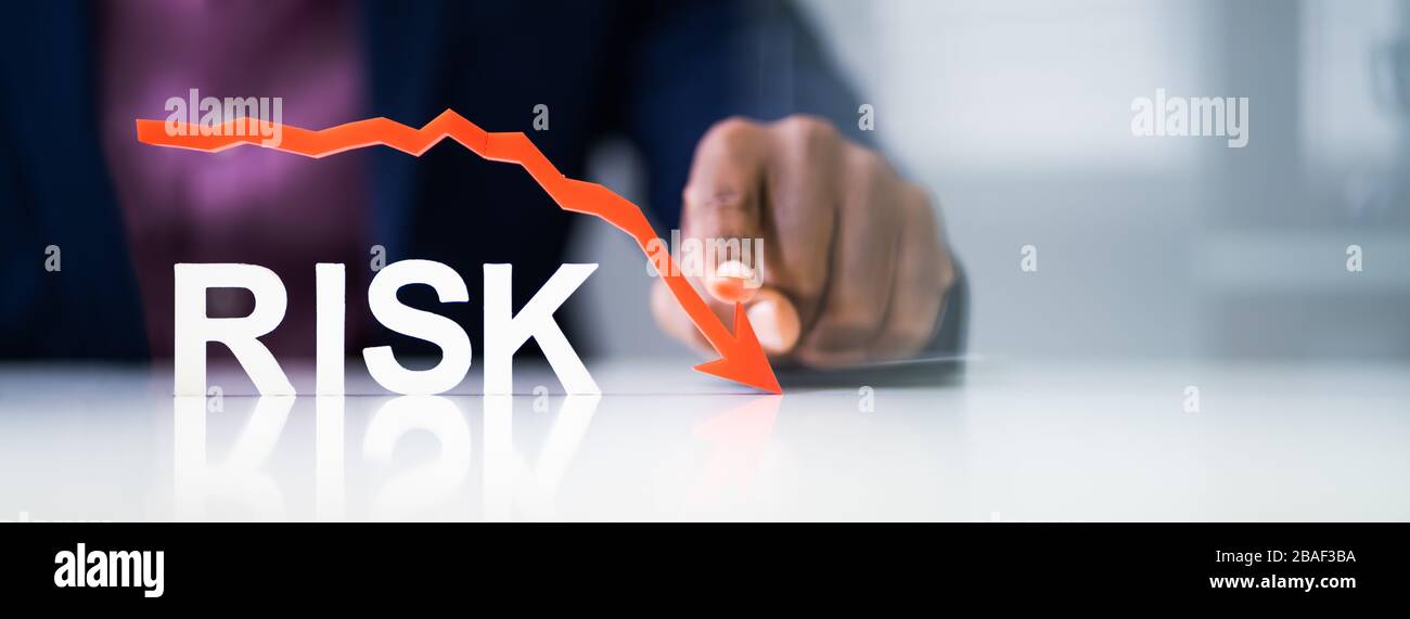 Unternehmer zeigen rote abnehmenden Pfeil über dem Risiko Text auf reflektierende Schreibtisch Stockfoto