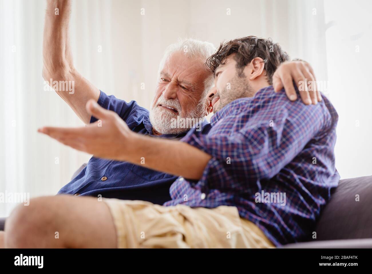 Alter Mann ernsthafte Diskussion mit jüngerem Mann im Innenbereich, Großvater ernsthafte Gespräche mit seinem Sohn zu Hause. Stockfoto