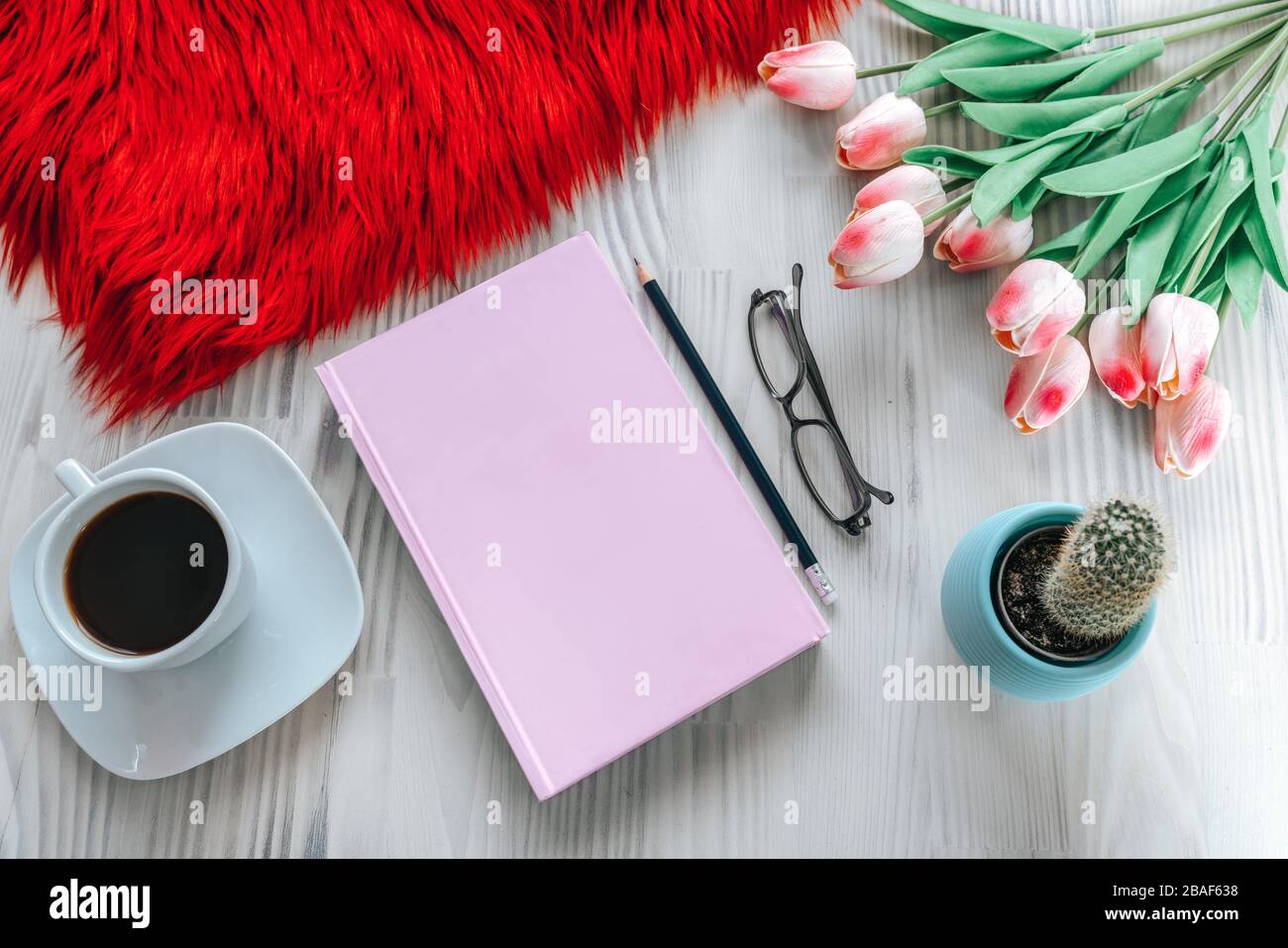 Bleistift und ein pinkfarbenes Notizbuch auf weißem Holztisch. Vogelperspektive, Mock-up-Konzept Stockfoto