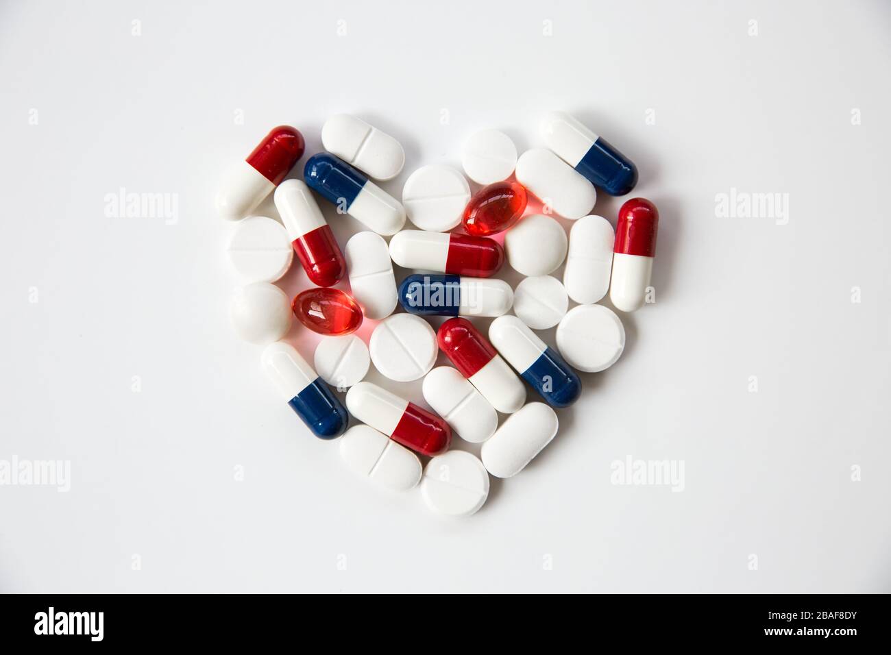 Herzpillen, Tabletten, Statine und Medikamente, die in Form eines Herzens auf weißem Hintergrund mit Kopierraum angeordnet sind Stockfoto