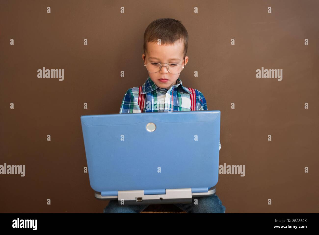 Portrait eines netten, ernsten Jungen mit einem Laptop. Kind in Brille mit Laptop Stockfoto