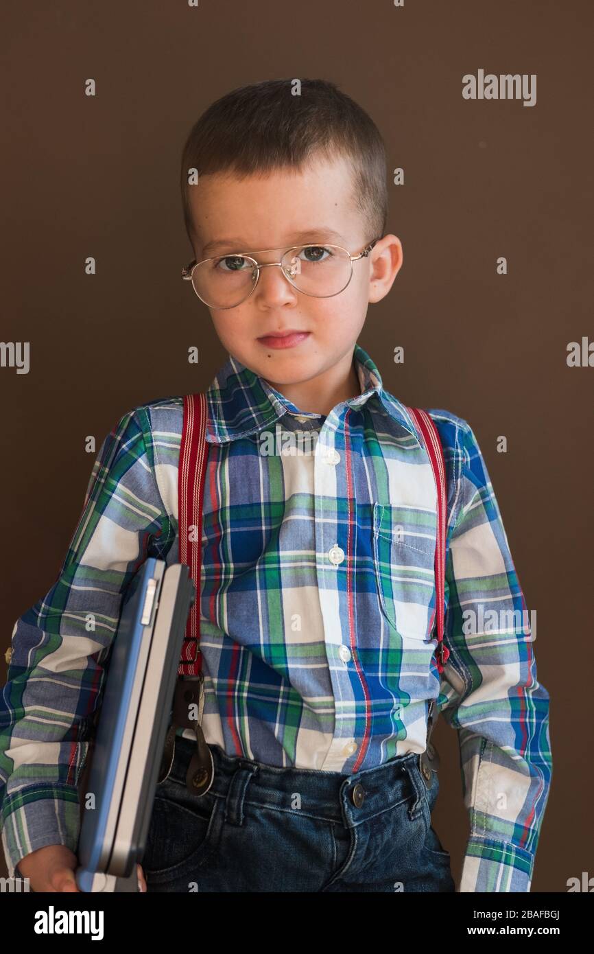 Portrait eines netten, ernsten Jungen mit einem Laptop. Kind in Brille mit Laptop Stockfoto