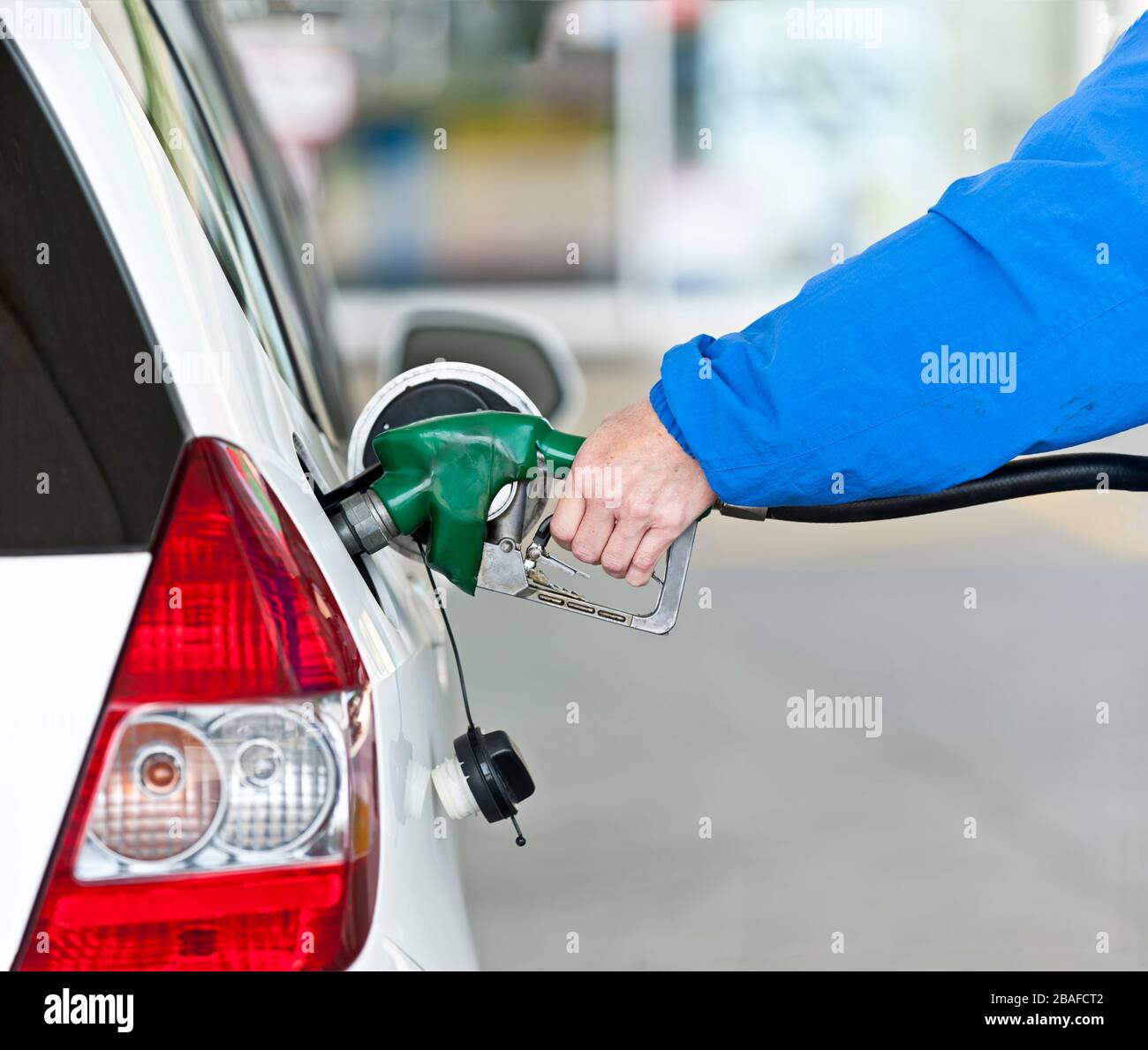 Horizontaler Schuss des Arms einer Frau und Hand, der Gas in ihr Auto pumpt. Stockfoto